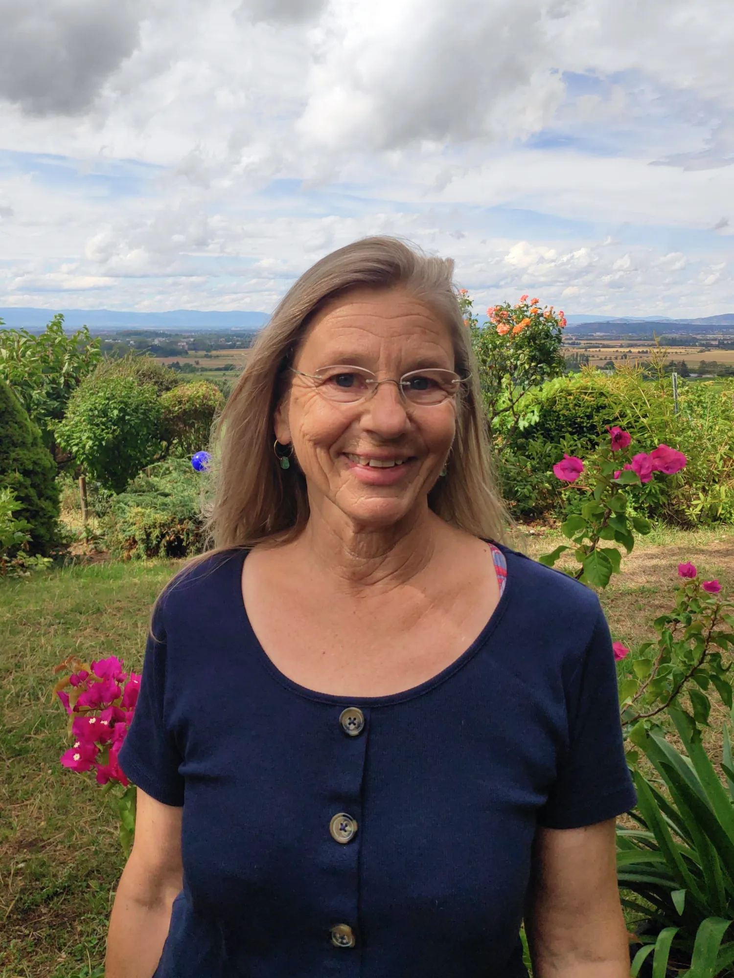 Eva-Maria lächelt vor einem blühenden Garten