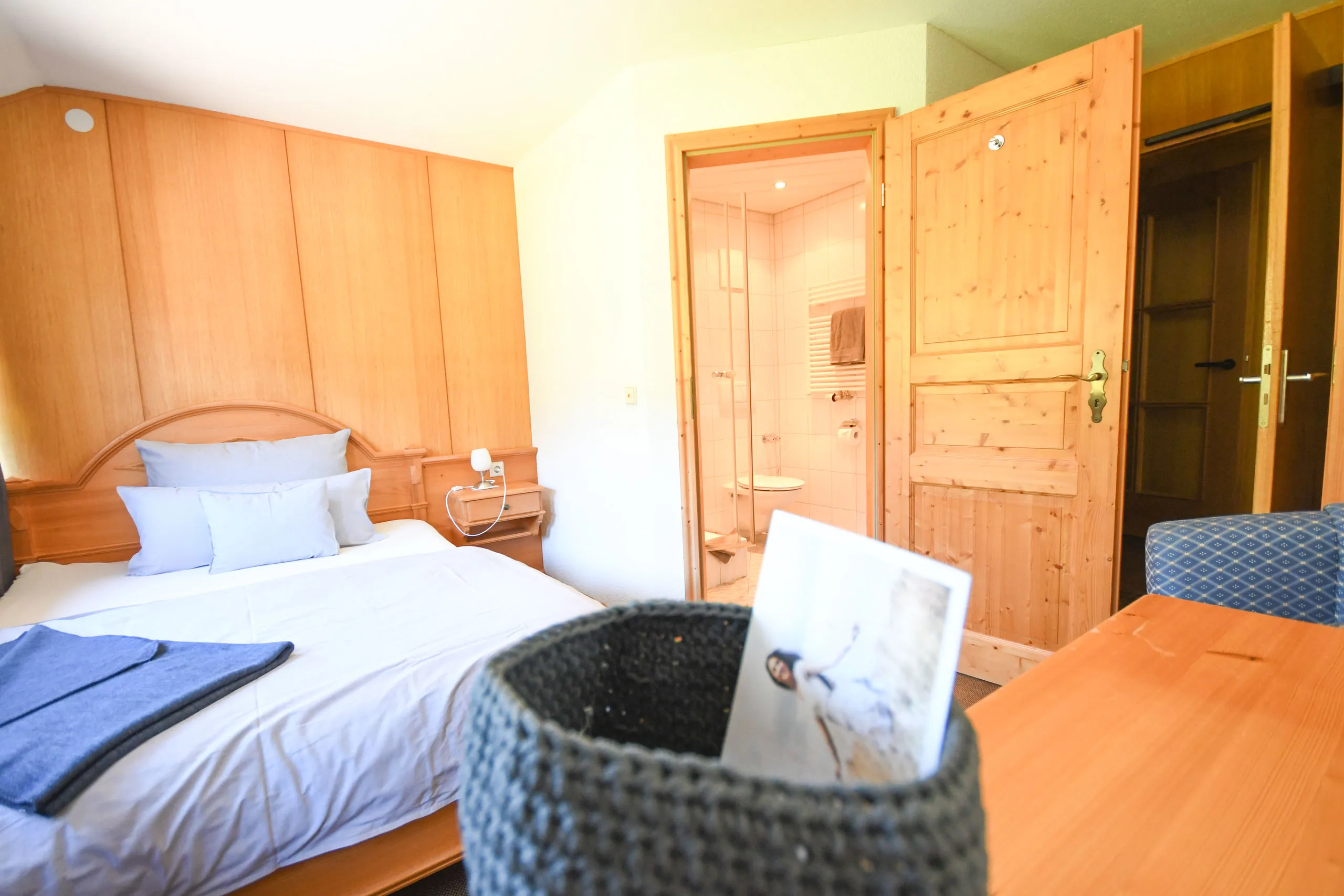 Ein Zimmer mit Bett, Holzwänden und offener Tür zum Bad